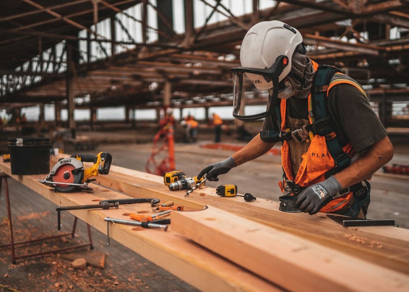 A carpenter measuring and cutting lumber at a workbench